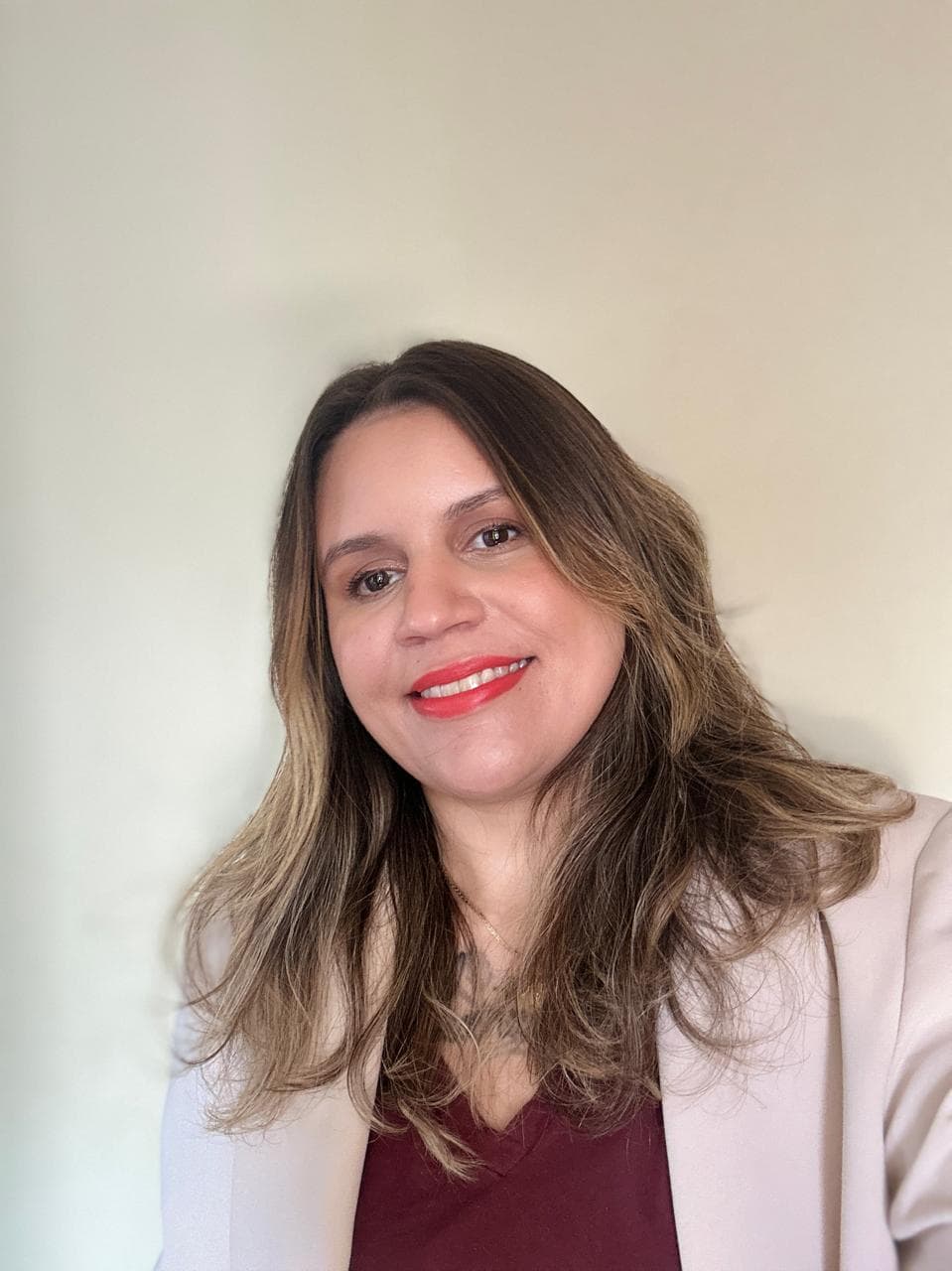 Retrato profissional de Natália Dantas, sorrindo e vestindo blazer claro